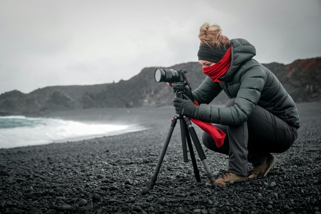 travel blogger using a camera tripod on a beach